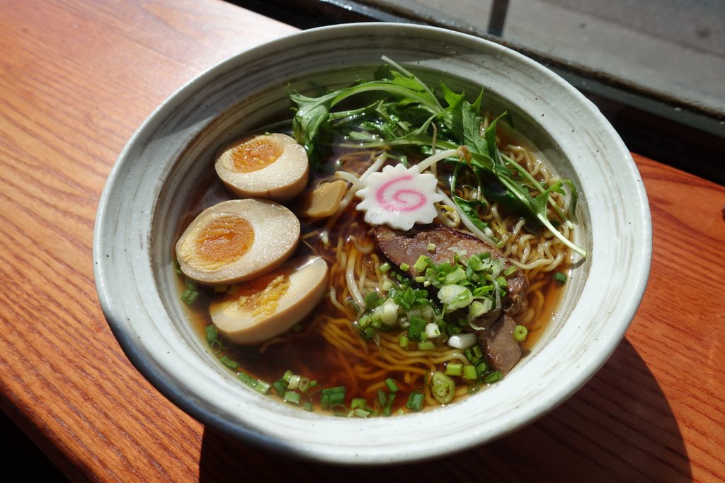 Bowl of shoyu ramen with clear golden broth, bamboo shoots, and negi green onions